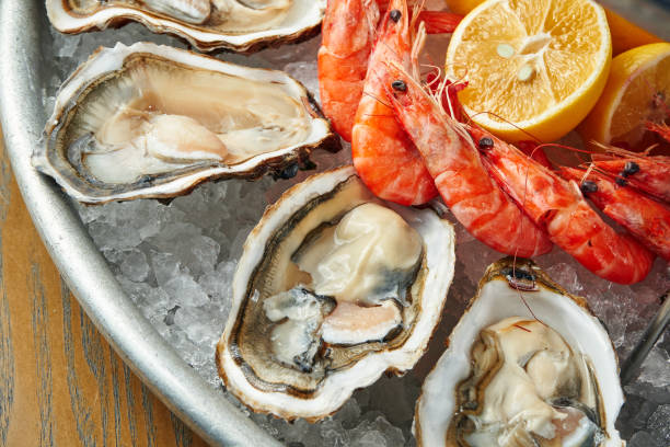istock Freshly cooked seafood in a plate on ice. Fresh oysters and prawns. Close up view, selective focus, wooden background 1222383767