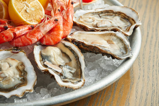 istock Freshly cooked seafood in a plate on ice. Fresh oysters and prawns. Close up view, selective focus, wooden background 1222383809