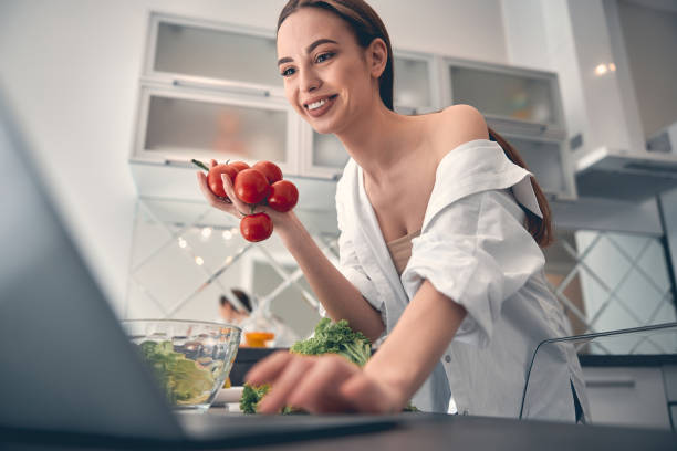 istock Caucasian positive lady cooking with vegetables in kitchen 1222384369
