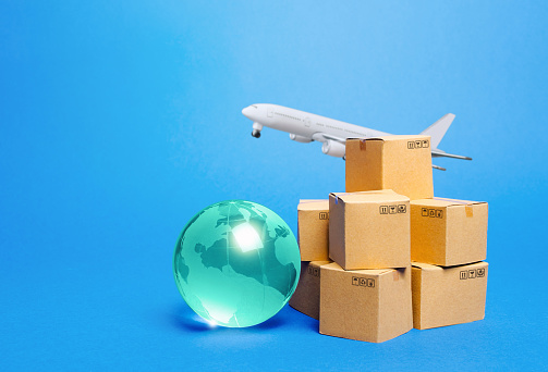 Blue globe, cardboard boxes and freight airplane. International world trade. Deliver goods, shipping. Import export freight traffic. Markets globalization. Using air transport to reduce delivery time.