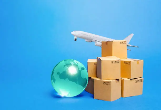 Photo of Blue globe, cardboard boxes and freight airplane. International world trade. Deliver goods, shipping. Import export freight traffic. Markets globalization. Using air transport to reduce delivery time.