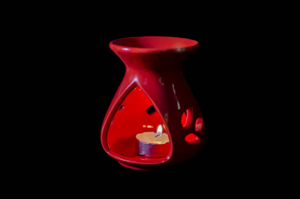 A red aroma oil lamp with wax lamp inside it. black backgroud and displaying it.