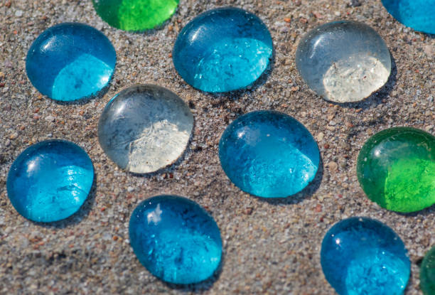 istock White, blue and green glass beads on sand 1222396317