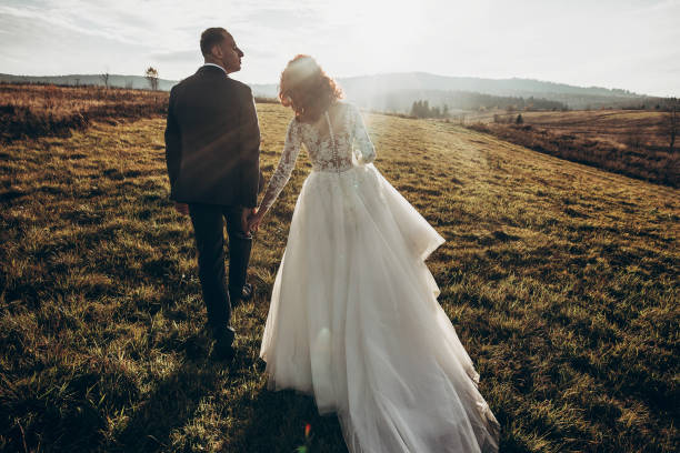 istock stylish bride and groom walking in sunlight, holding hands in mountains at sunset light. gorgeous boho newlywed couple, true feelings. emotional romantic moment. space for text 1222399270