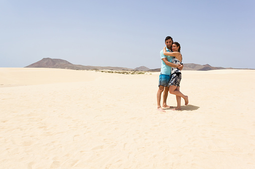 Man and woman posing on desert in Fuerteventura island, Spain. Summer tourism, popular travel destination concepts