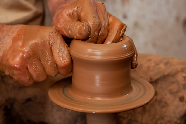 Hands of a potter, creating an earthen jar on the circle.