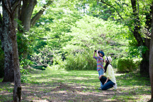 Mother and daughter playing with binoculars in the woods