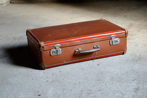 Brown vintage suitcase on gray background. side-view. concrete floor.