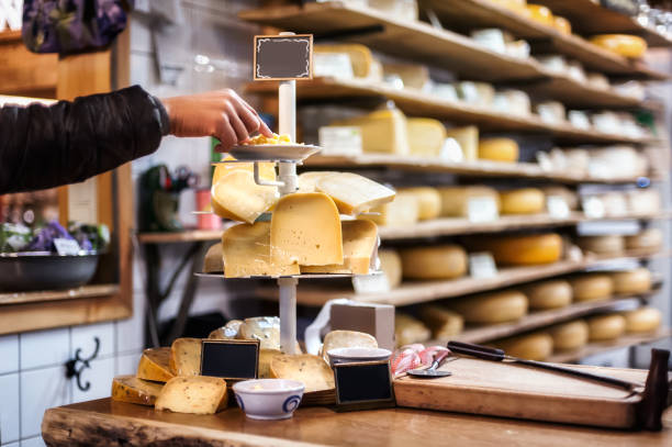 woman tasting and choosing organic dutch cheese on the shop - gouda imagens e fotografias de stock