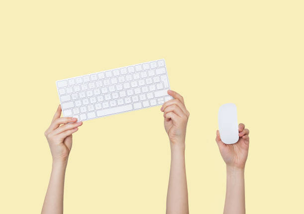 istock Raising hands with keyboard and mouse on yellow background 1222414018