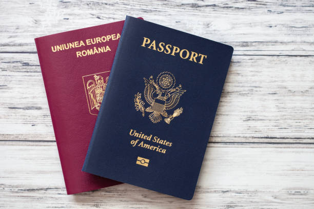 American and Romanian passports flat lay on a wooden background. Double citizenship concept. stock photo