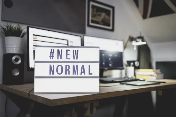 Photo of Light signs with text hashtag #NEW NORMAL on the working desk. Work from home. New normal concept. Social distancing.