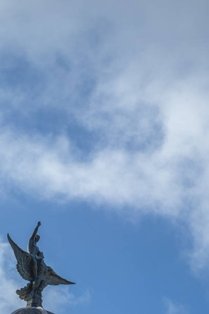 istock Statue with wings with a blue sky background and clouds.  Winged statue with a blue sky and clouds background 1222419674