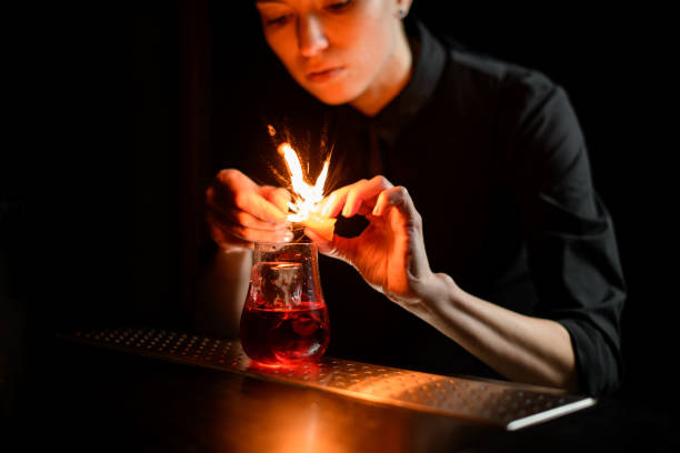 istock close-up barman gently sprinkles on glass with red cocktail and ice and make fire. 1222419829