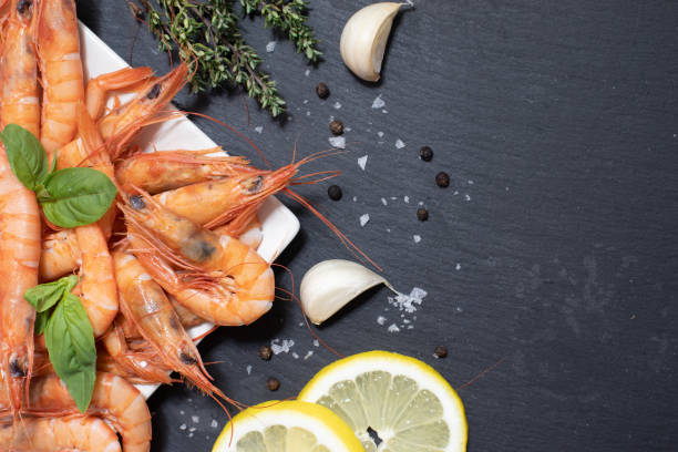 istock Red boiled shrimps with garlic and lemon on dark background 1222420896