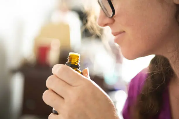This is a photograph of a real woman smelling essential oil during lockdown at home in Miami, Florida.