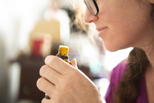 woman smells aromatherapy essential oil in the morning during lockdown - aromatic oil imagens e fotografias de stock