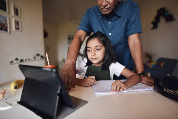 istock Grandfather helps granddaughter during online class 1222421345