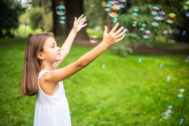 istock Cute small girl playing with soap bubbles in nature 1222422527