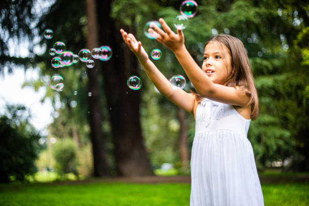 istock Cute small girl playing with soap bubbles in nature 1222422840