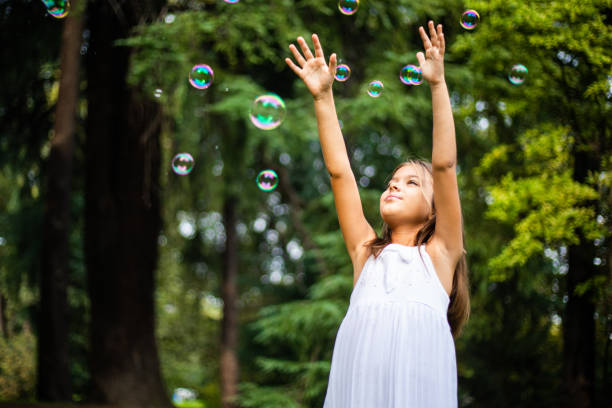 istock Cute small girl playing with soap bubbles in nature 1222423014