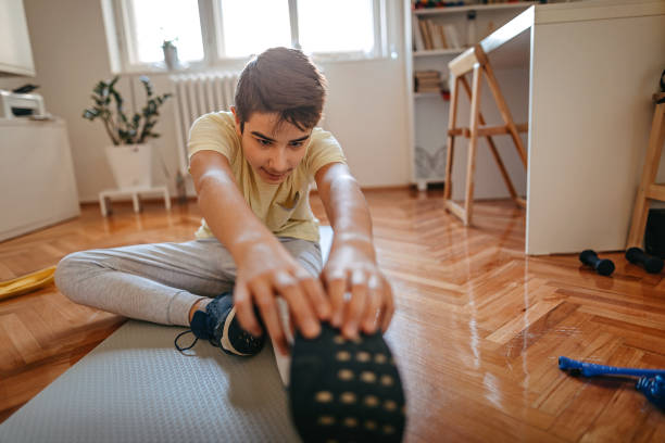 Boy stretching and touching toes on exercise mat at home
