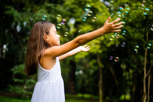 istock Cute small girl playing with soap bubbles in nature 1222423199