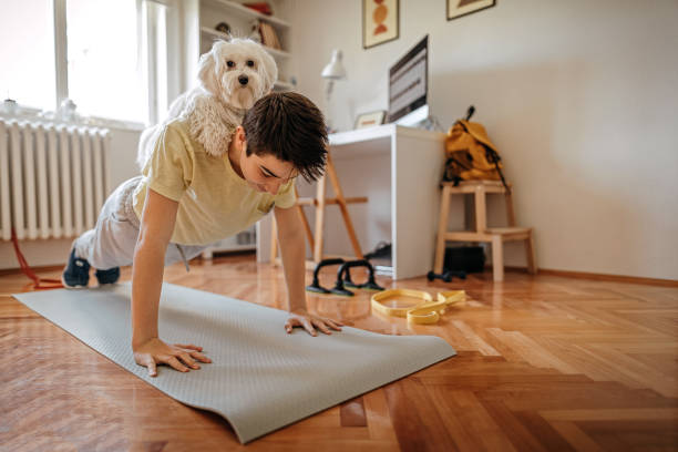 Boy exercising with his pet Maltese dog at home Teenage boy doing exercise with his pet Maltese dog sitting on his back at home exercise room stock pictures, royalty-free photos & images