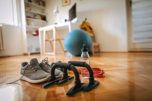 Push up bars, sports shoe, resistance band and water bottle for exercise on hardwood floor