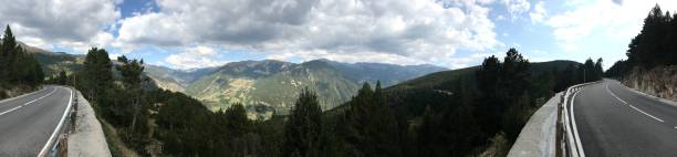 istock A panoramic view of mountains in the Andorran Pyrenees with a road either side and cloudy blue skies with forests all around 1222425049