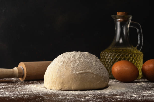 istock Fresh raw dough for bread or pizza with eggs and oil on a dark wooden table. 1222425138