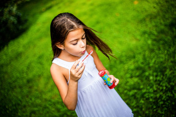 istock Cute girl playing with soap bubbles in nature 1222425273