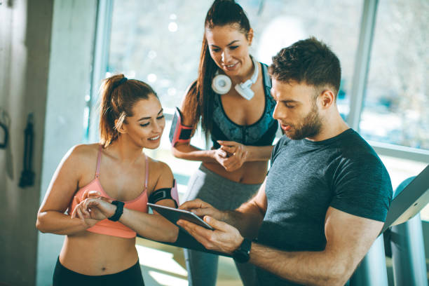 istock Personal trainer looking at digital tablet and explaining progress to young women at the gym 1222427803