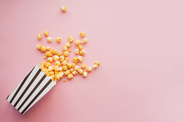 istock Popcorn in paper bag scattered on pink background top view 1222429222