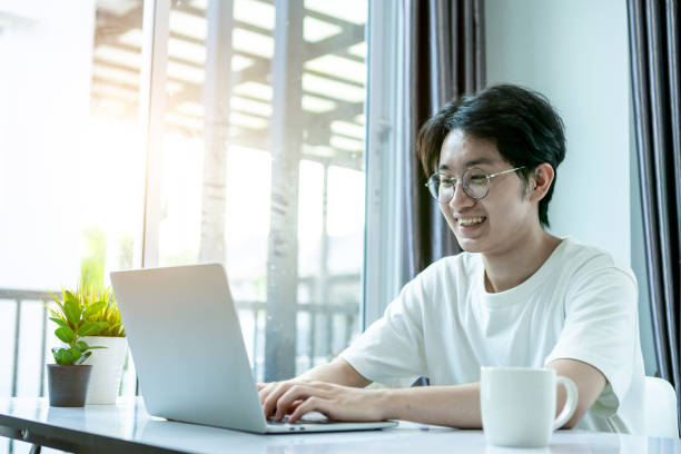 istock Asian man working from home, he use laptop and tablet and drinking coffee in covid-19 virus situation. Her working in quarantine for coronavirus. Work from home concept. 1222430452