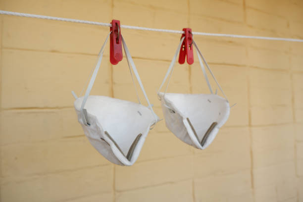 istock White medical reusable face respirators hung for drying on yellow brick wall background. Washing for mask reuse. Shortage of masks during the Coronavirus Covid-19 pandemic 1222430805