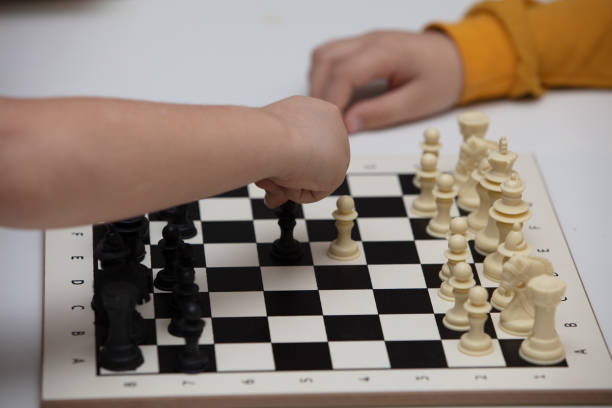 istock sits at a table and plays chess. The kid concentrated on the game and thinks where to make his next move. Early development, home educational games for children 1222433612