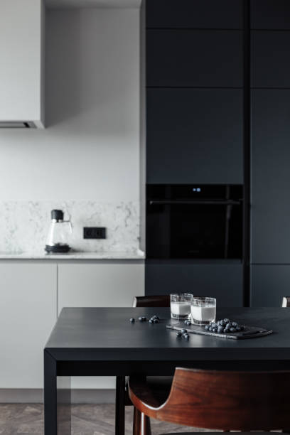 istock bright kitchen with dark table, convenient location of kitchen accessories and equipment, modern style, White walls, marble working surface and parquet floor. There s a glass of milk on the table and a blueberry 1222435492
