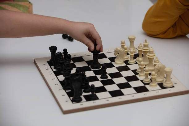 istock sits at a table and plays chess. The kid concentrated on the game and thinks where to make his next move. Early development, home educational games for children 1222435716