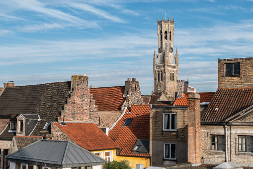 Cityscape with belgian famous Belfry tower high above the roofs of the brick houses in the city centre of Bruges, Belgium.