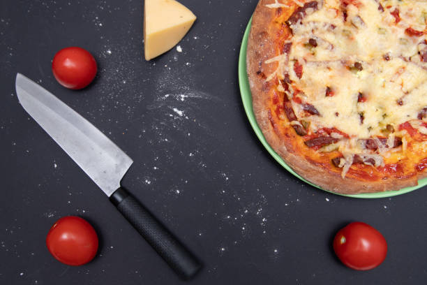 istock Pizza on a black background with a knife and ingredients. 1222442076