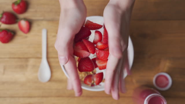 Strawberries falling in a bowl of yogurt with granola
