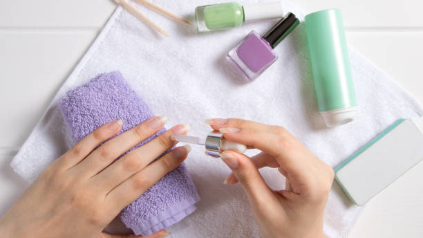 マニキュア。女性はキューティクルに保湿剤を塗布します。マニキュアツール、マニキュア、オイル。ホームネイルケア、スパ、美容。長い自然な爪。美容室。 - 手の爪 写真 ストックフォトと画像