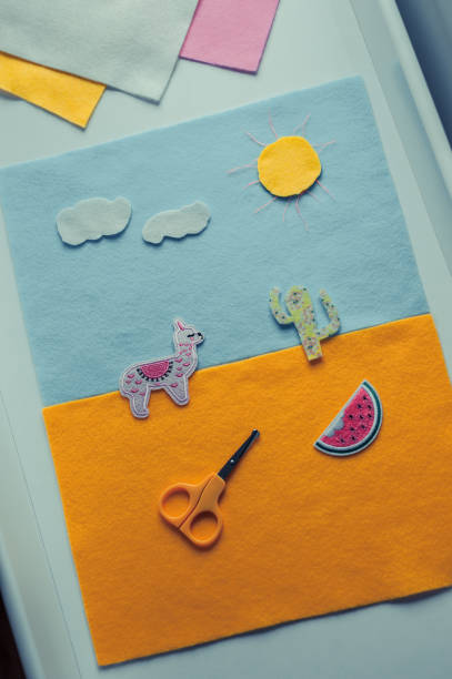 istock Kid is making a collage. Cutting shapes from colored paper to glue it on a base layer. Working with scissors, improving craft skills. 1222445121