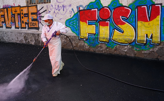 Bucharest, Romania - April 23, 2020: Sanitation employees clean the streets with environmentally active foam in an attempt to eliminate the spread of coronavirus.