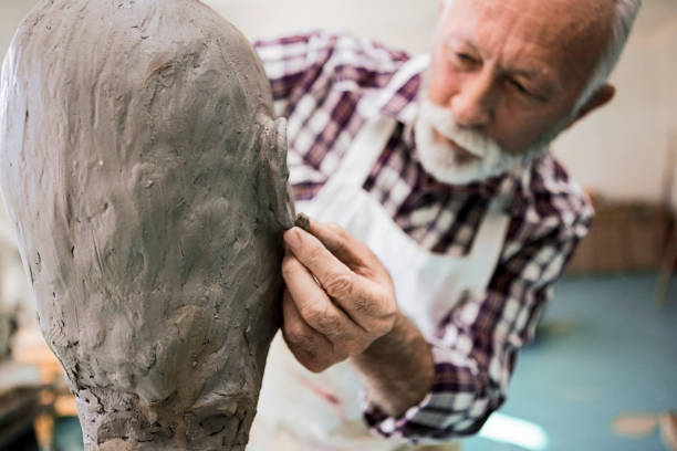 istock Senior man making statue of clay shaping ear 1222452016