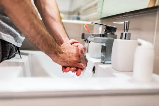 Cropped shot of an unrecognizable man washing his hands in the bathroom at home.