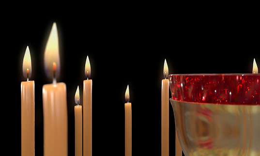 Candle flame burning steadily on a bottom left corner of a frame on a black background