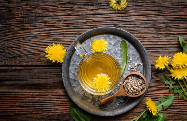 Herbal drink for liver detox, dandelion root tea in a glass cup decorated with fresh flowers with copy space stock photo