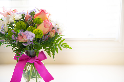 Bouquet of flowers with pink roses, brassica flower, chrysanthemum and freesia flower in a vase isolated on a white background.